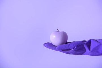 ウルトラ バイオレットに分離された紫色のリンゴを保持しているゴム手袋の手でトリミング ビュー ロイヤリティフリー写真 画像素材